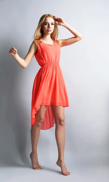 Modelo joven expresivo en vestido naranja sobre fondo gris —  Fotos de Stock