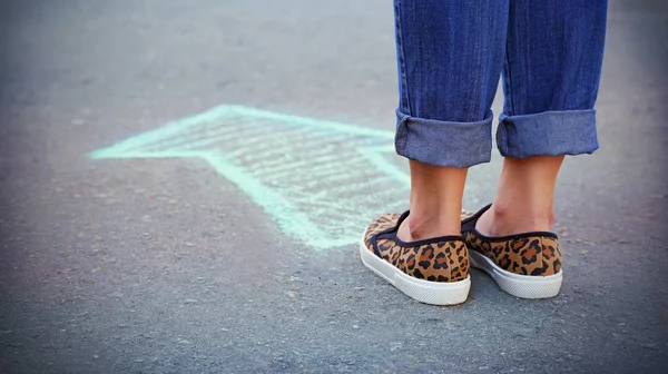 Female feet and drawing arrow on pavement background — Stock Photo, Image