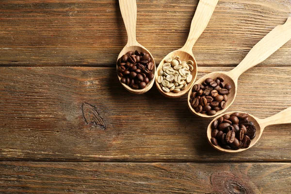 Granos de café en cucharas sobre fondo de madera — Foto de Stock