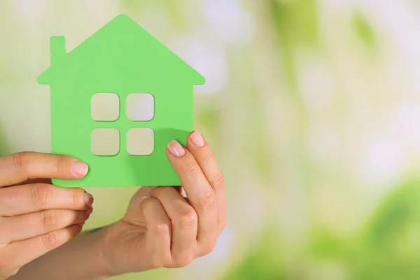 Female hands with model of house on blurred background — Stock Photo, Image