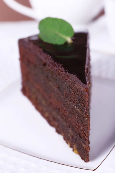 Κομμάτι του κέικ σοκολάτας με μέντα στο άσπρο πιάτο, κινηματογράφηση σε πρώτο πλάνο — Φωτογραφία Αρχείου