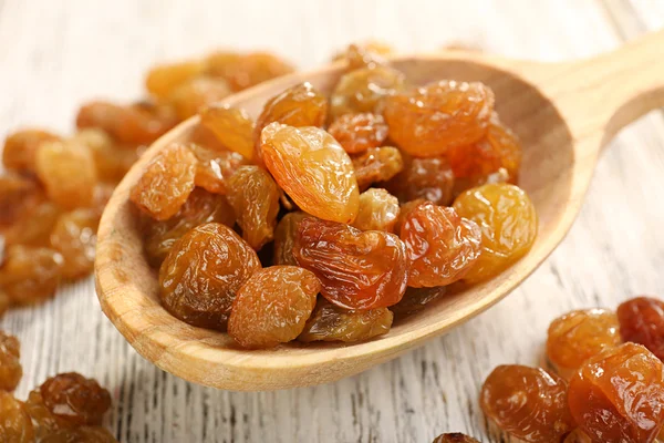 Raisins in spoon on wooden table, closeup — Stock Photo, Image