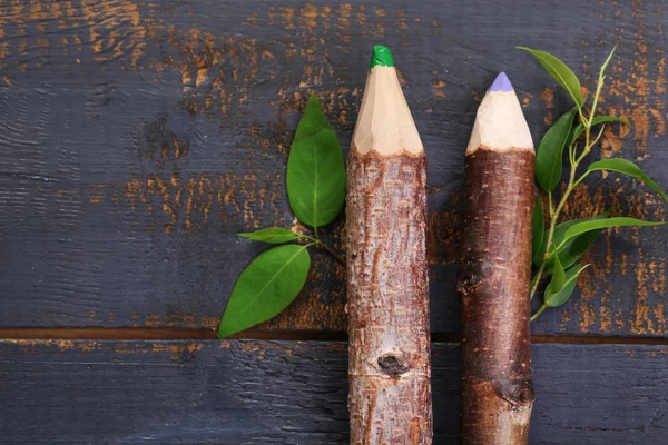 Деревянные карандаши с листьями на деревянном фоне — стоковое фото