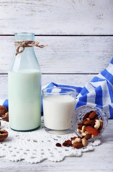 Leche en cristalería con nueces y galletas sobre fondo de madera —  Fotos de Stock