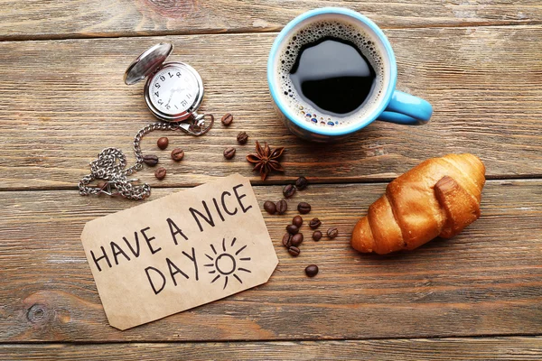 Cup of coffee with fresh croissant and Have A Nice Day massage on wooden table, top view — Stock Photo, Image