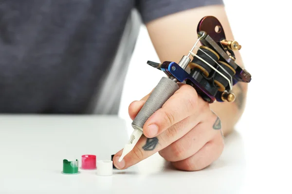 Mano del tatuatore con macchina del tatuaggio e inchiostro colorato isolato su bianco — Foto Stock