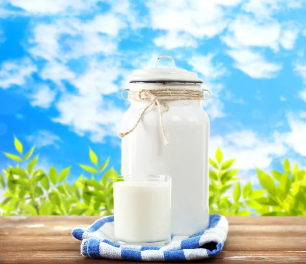 Ретро банку для молока і склянки молока на дерев'яному столі, на білому тлі — стокове фото