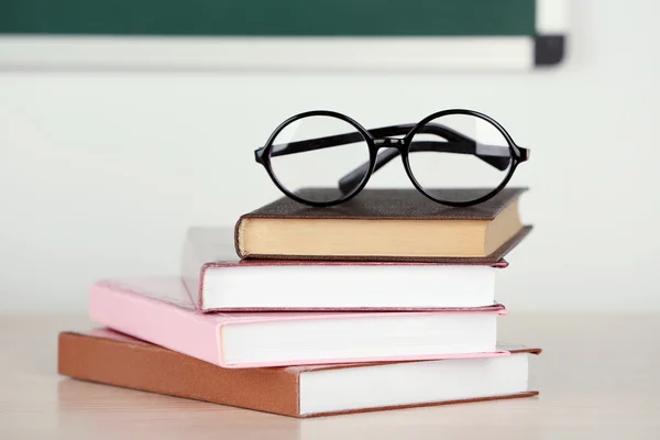 Heap of books and glasses on table in class — Stock Photo, Image