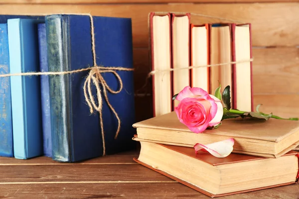 Livros amarrados com rosas cor-de-rosa em fundo de madeira — Fotografia de Stock