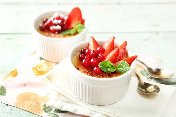 Creme brulee dessert with fresh strawberry and mint leaves, on color wood background — Stok Foto