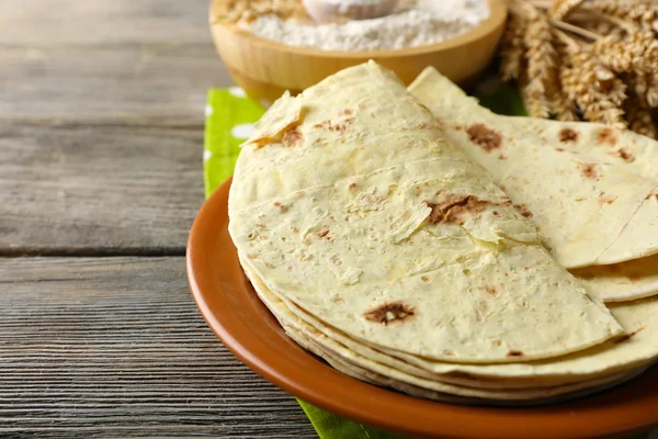 Stack of homemade whole wheat flour tortilla on plate, on wooden table background — Stock Photo, Image