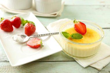Creme brulee tatlısı peçeteye renk ahşap arka plan üzerinde taze çilek Çilek ile