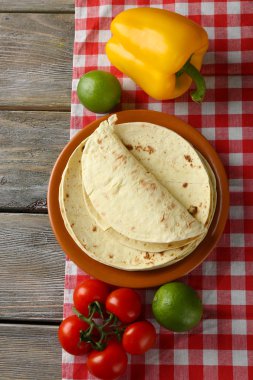 ev yapımı kepekli un tortilla ve ahşap masa arka plan üzerinde plaka üzerinde sebze yığını