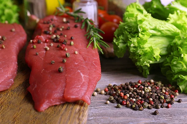 Raw beef steak with spices and greens on table close up — Stock Photo, Image