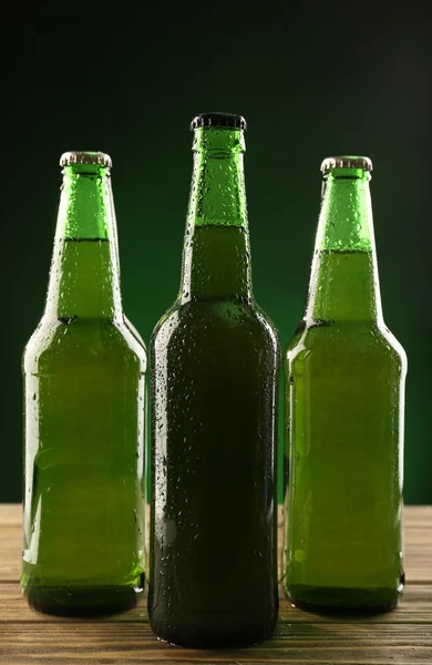 Botellas de vidrio de cerveza sobre fondo verde oscuro — Foto de Stock