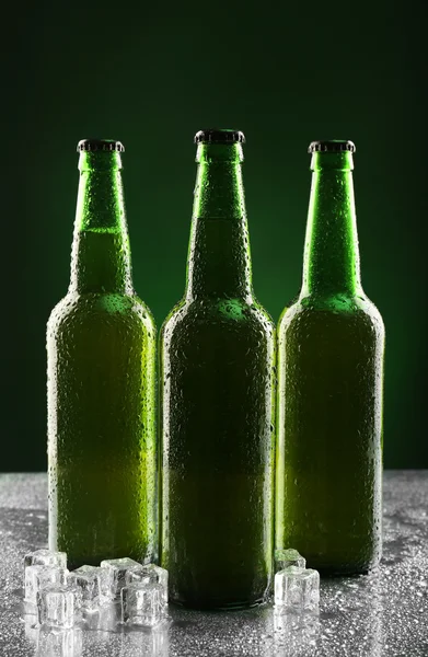 Glasflaschen Bier mit Eiswürfeln auf dunklem Hintergrund — Stockfoto