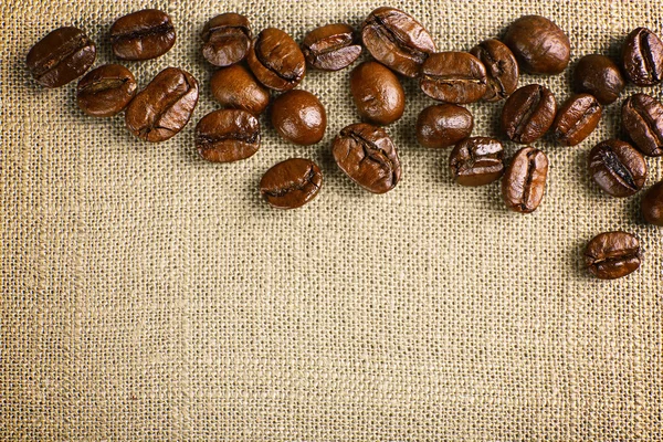 Frame of coffee beans on color sackcloth background — Stock Photo, Image