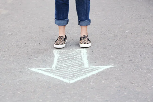 Жіночі ноги і малюнок стрілки на фоні тротуару — стокове фото