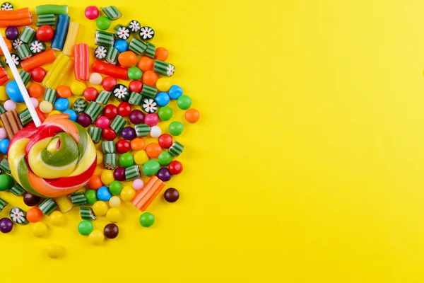 Colorful candies on yellow background — Stock Photo, Image