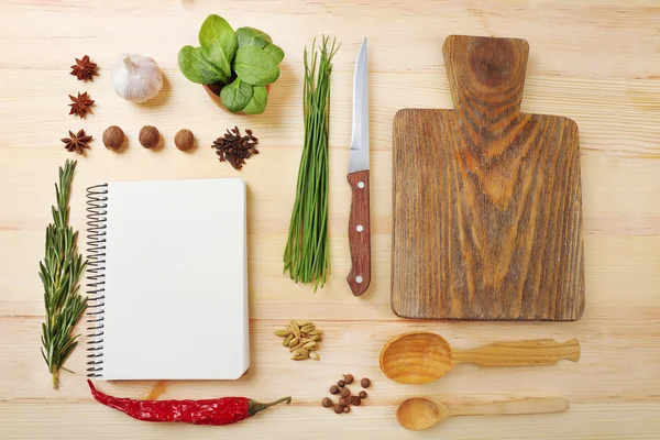 Open recipe book with fresh herbs and spices on wooden background