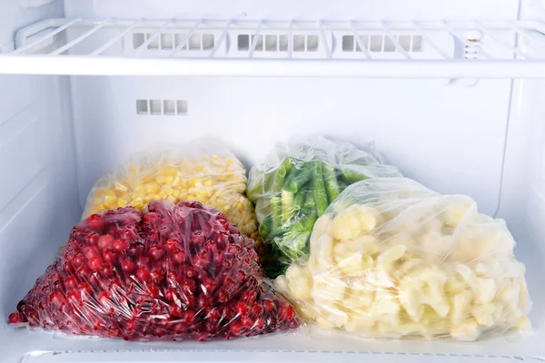 Frozen berries and vegetables in bags in freezer close up — Stock Photo, Image