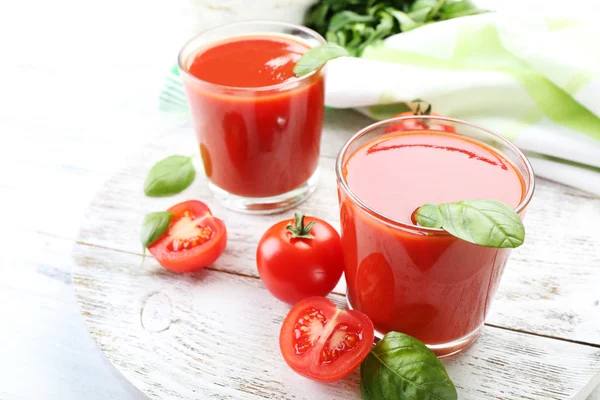 Verres de jus de tomate frais sur table en bois, gros plan — Photo