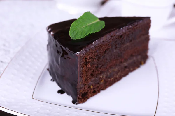 Pezzo di torta al cioccolato con menta su piatto bianco, primo piano — Foto Stock