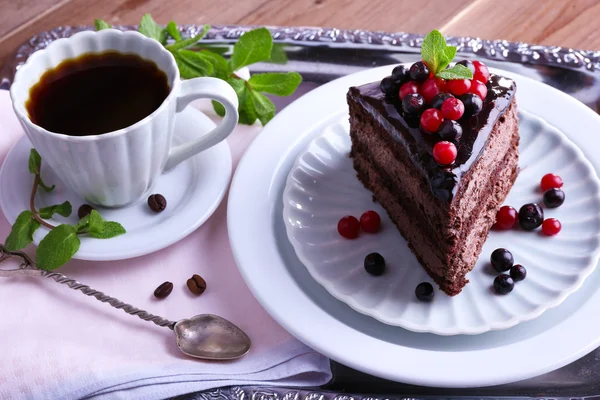 Delicioso pastel de chocolate con bayas y taza de café en la mesa de cerca — Foto de Stock