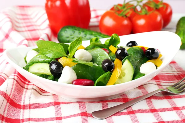 Färska grönsaker sallad i skål på bordet på nära håll — Stockfoto