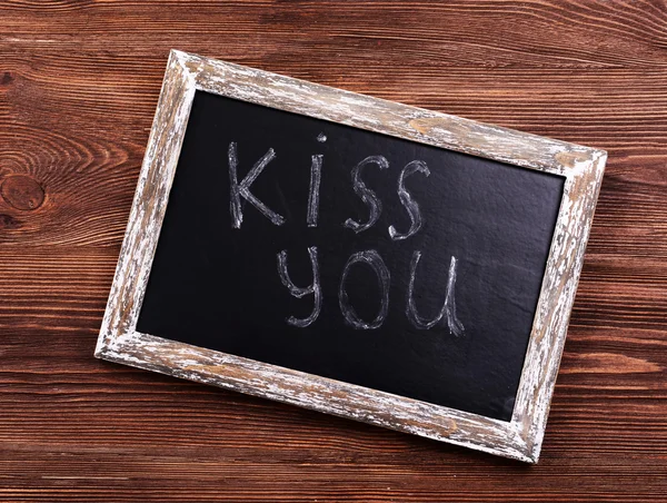 Inscription KISS YOU on blackboard on wooden background — Stock Photo, Image