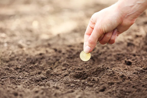 Mano hembra plantando moneda en el suelo — Foto de Stock