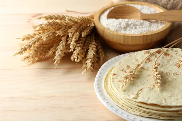 Stack of homemade whole wheat flour tortilla on plate, on wooden table background — Stock Photo, Image