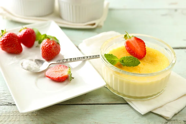 Sobremesa de brulee de creme com bagas de morango frescas em guardanapo, no fundo de madeira a cores — Fotografia de Stock