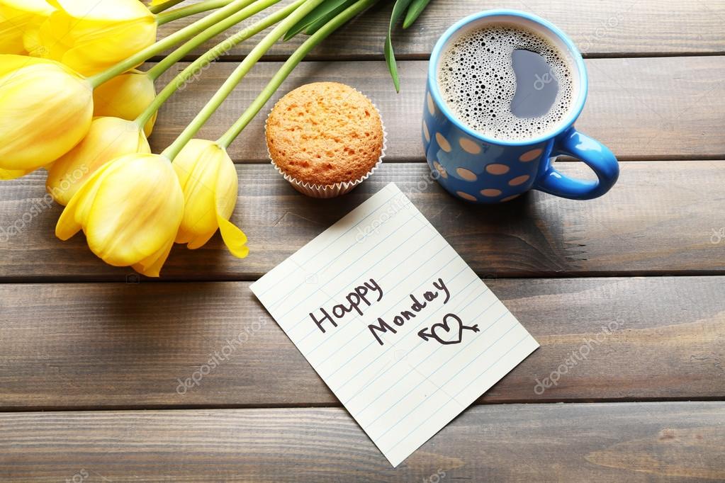 Cup of coffee with fresh cupcake, tulips and Happy Monday massage on wooden background