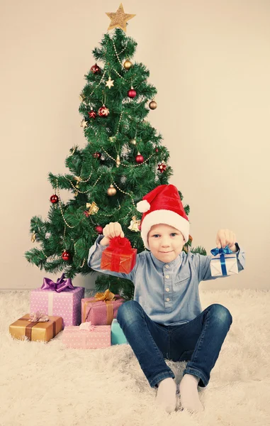 礼品附近在房间里的圣诞树上的小男孩 — 图库照片