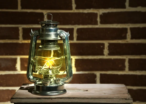 Burning kerosene lamp on brick wall background — Stock Photo, Image