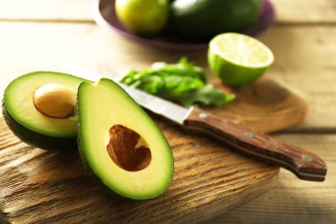 Ahşap arka plan üzerinde kesme tahtası üzerinde avokado ve limon kireç dilimlenmiş