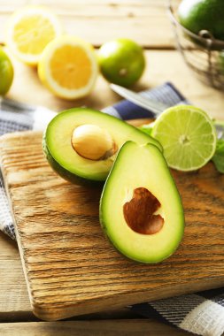Ahşap arka plan üzerinde kesme tahtası üzerinde avokado ve limon kireç dilimlenmiş