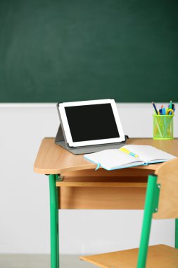 İleti örneği ve yazı tahtası arka plan üzerinde sınıfta tablet ile ahşap masa