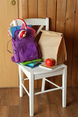 Okul malzemeleri ile sandalye ahşap arka plan üzerinde sırt çantası