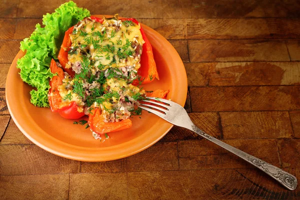 Stuffed red pepper with lettuce on plate on wooden table — Stock Photo, Image