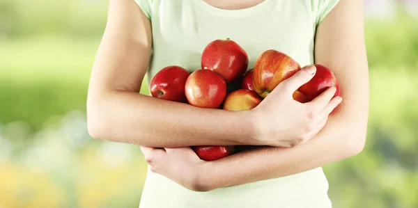 Pommes rouges dans les mains de la femme sur fond de nature — Photo