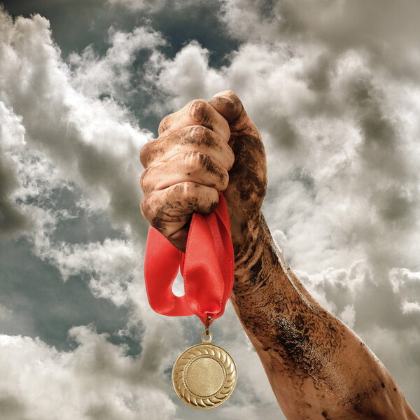 Golden medal in hand on sky background
