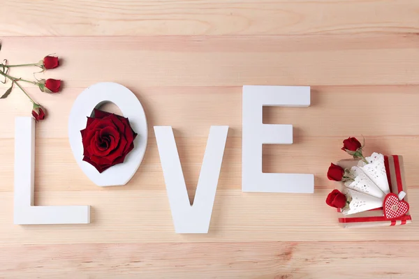 Hermosas rosas con palabra AMOR y caja de regalo sobre tablones de madera fondo — Foto de Stock