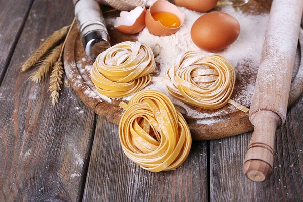 Raw homemade pasta and ingredients for pasta on wooden background — Stock Photo, Image