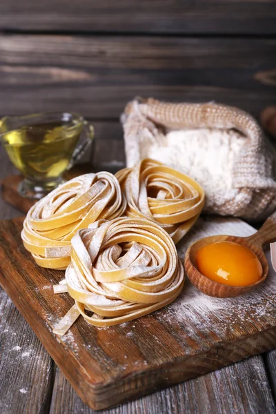 Pasta mentah buatan sendiri dan bahan-bahan untuk pasta pada latar belakang kayu — Stok Foto