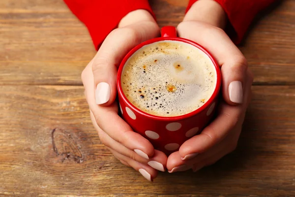 Mani femminili che tengono la tazza di caffè su sfondo di legno — Foto Stock