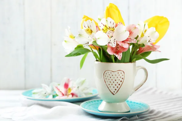 Vackra blommor i cup, på trä bakgrund — Stockfoto