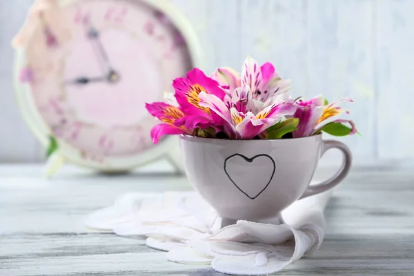 Schöne Blumen in Tasse, auf Holzgrund — Stockfoto