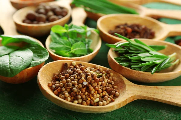 Wooden spoons with fresh herbs and spices on wooden background — Stock Photo, Image